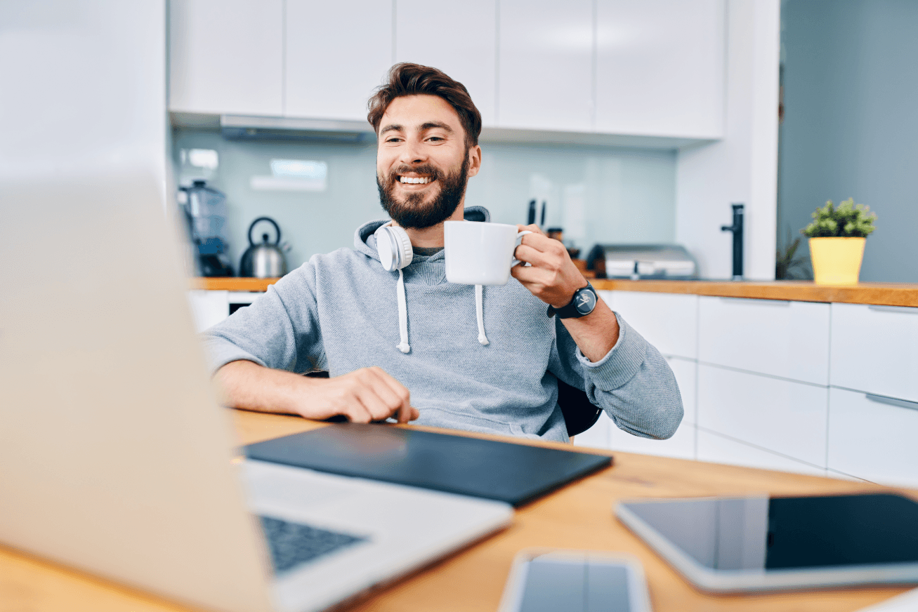 A man drinks coffee in front of his computer during a virtual meeting