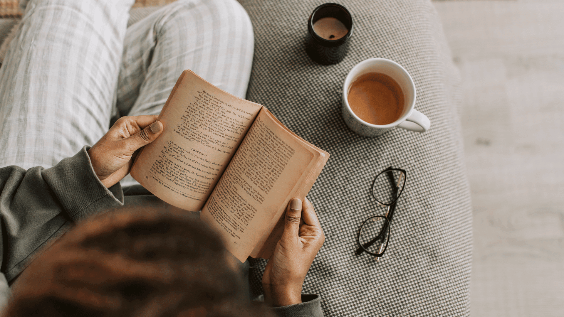 Overhead view of a person reading a book with coffee
